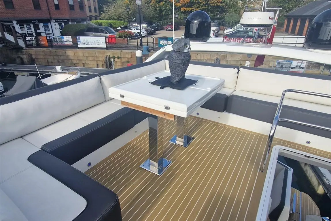 Luxury boat deck featuring a stylish table with a black owl sculpture and elegant cushioned seating.
